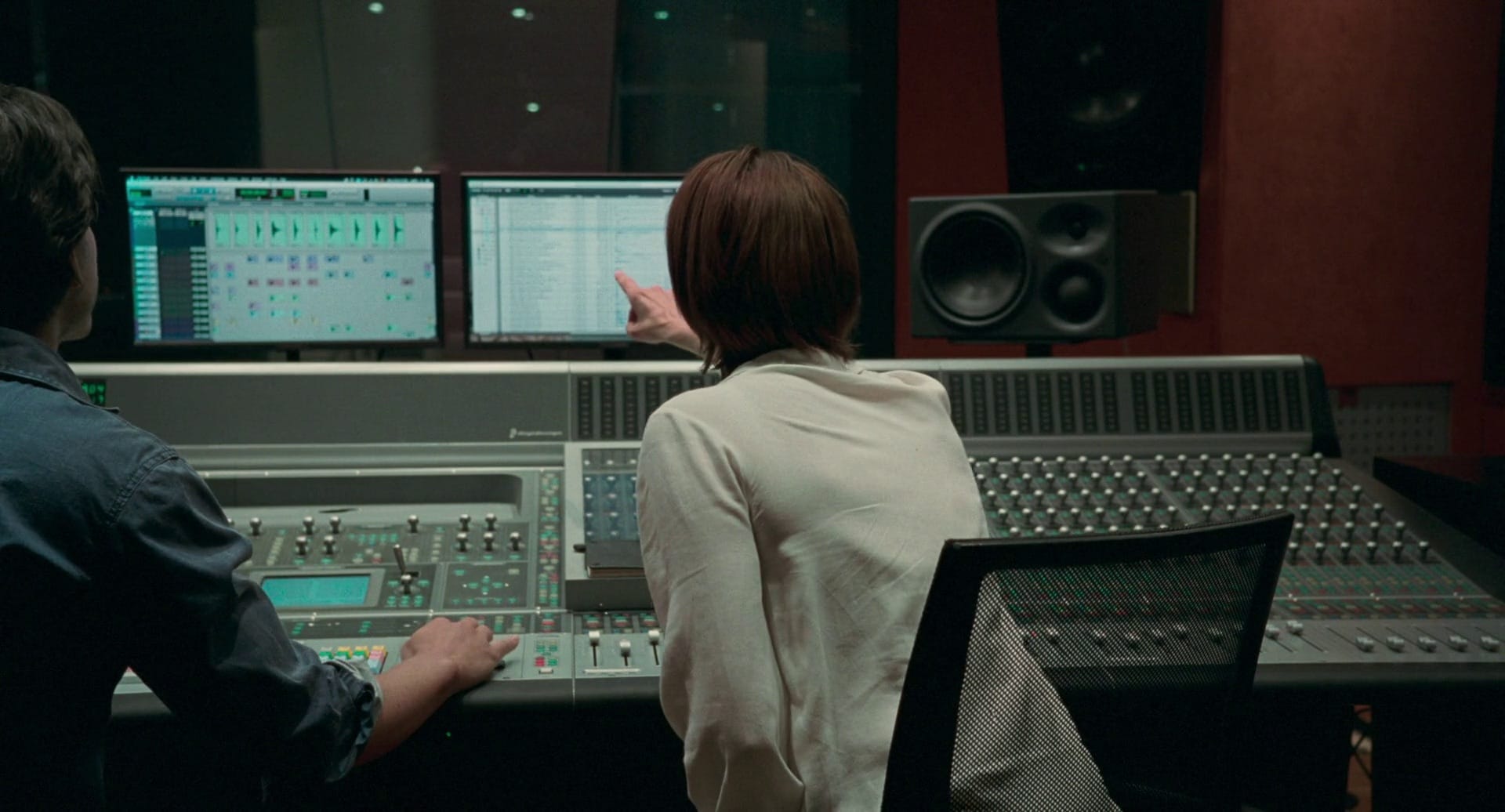 Two music producers in the studio working on a music project with a DAW open