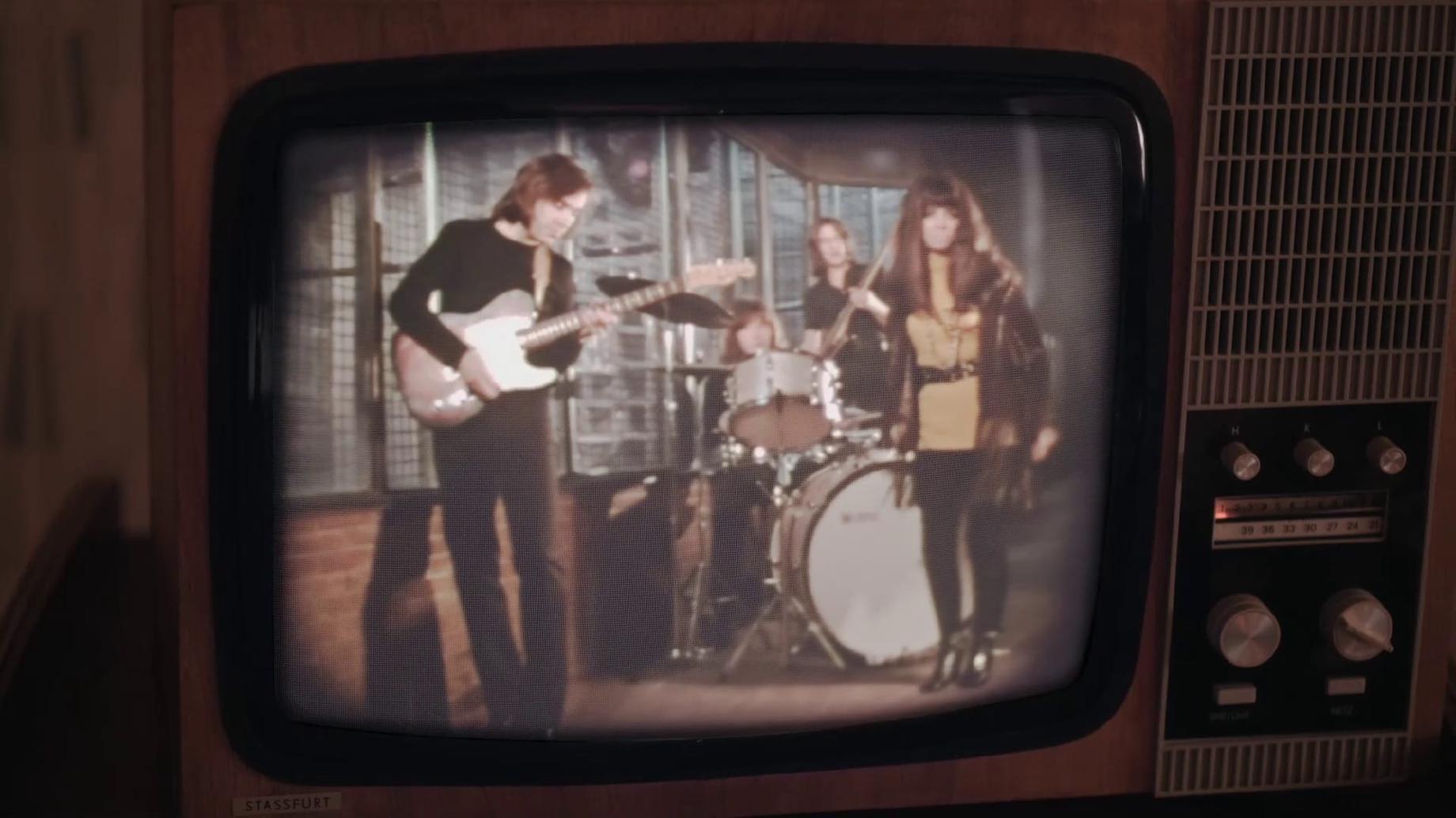 Un groupe qui joue un concert diffusé sur une télévision ancienne