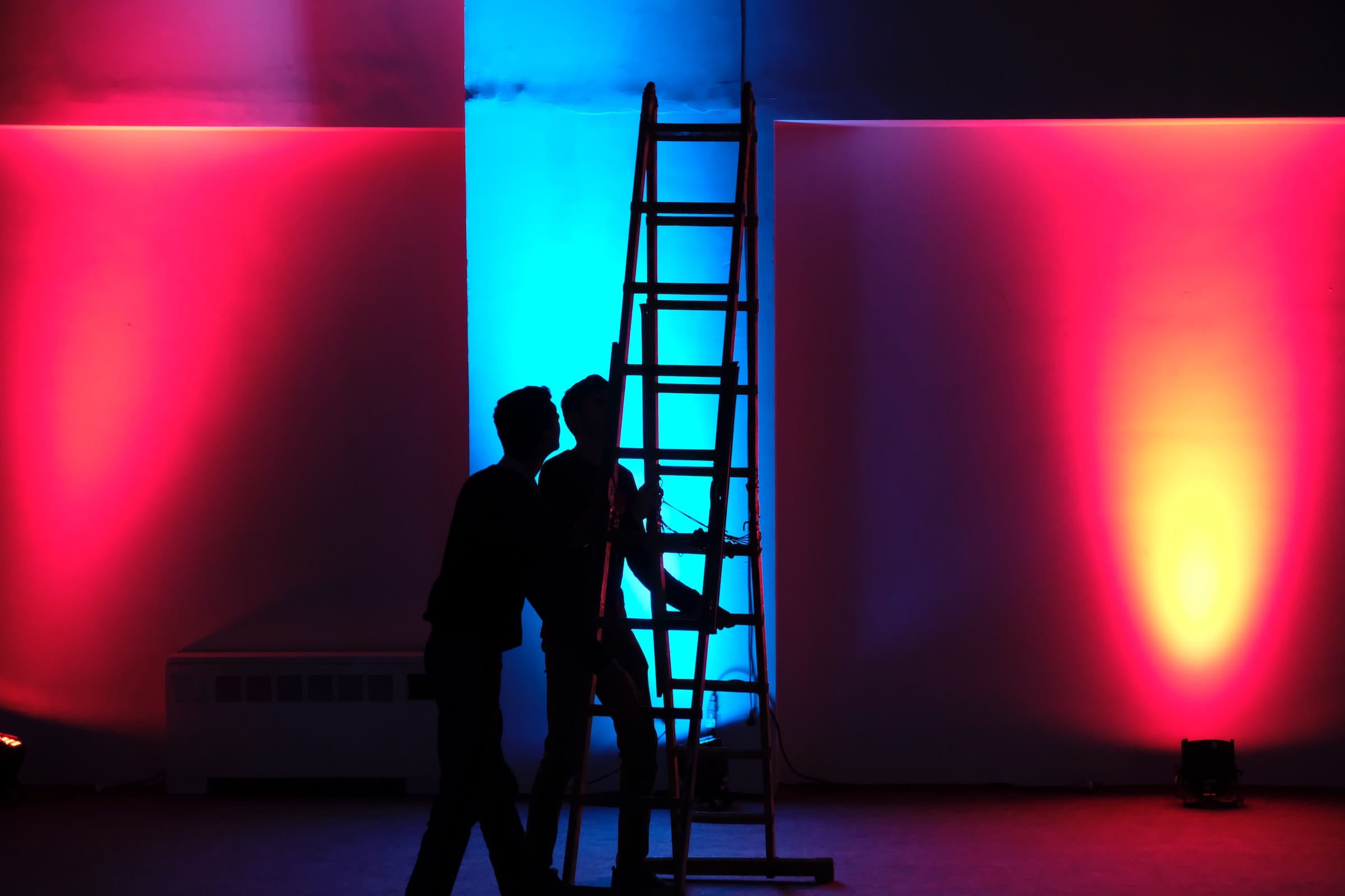 Two men working lights on a shooting set.