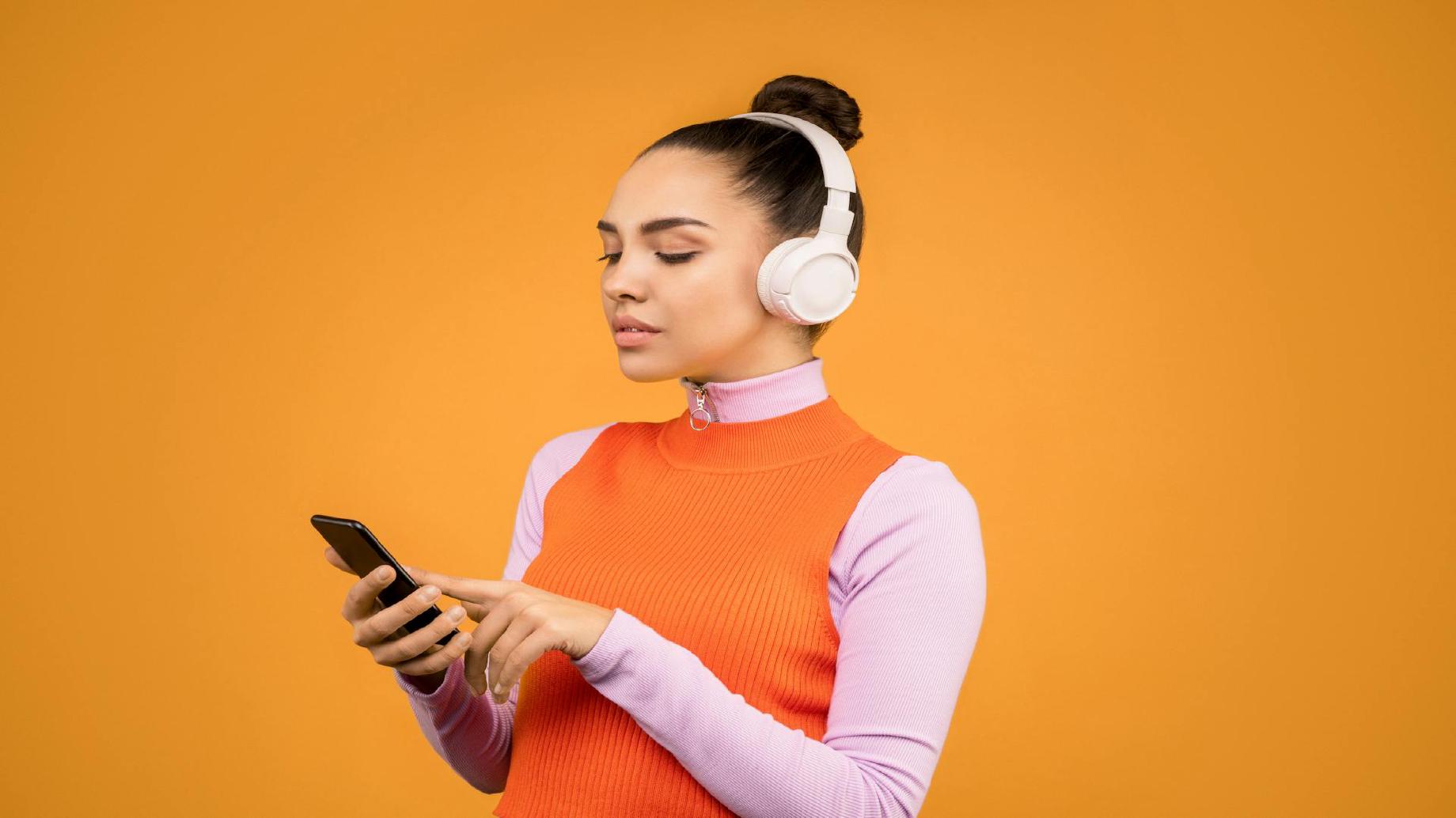 A woman listens to music with white headphones