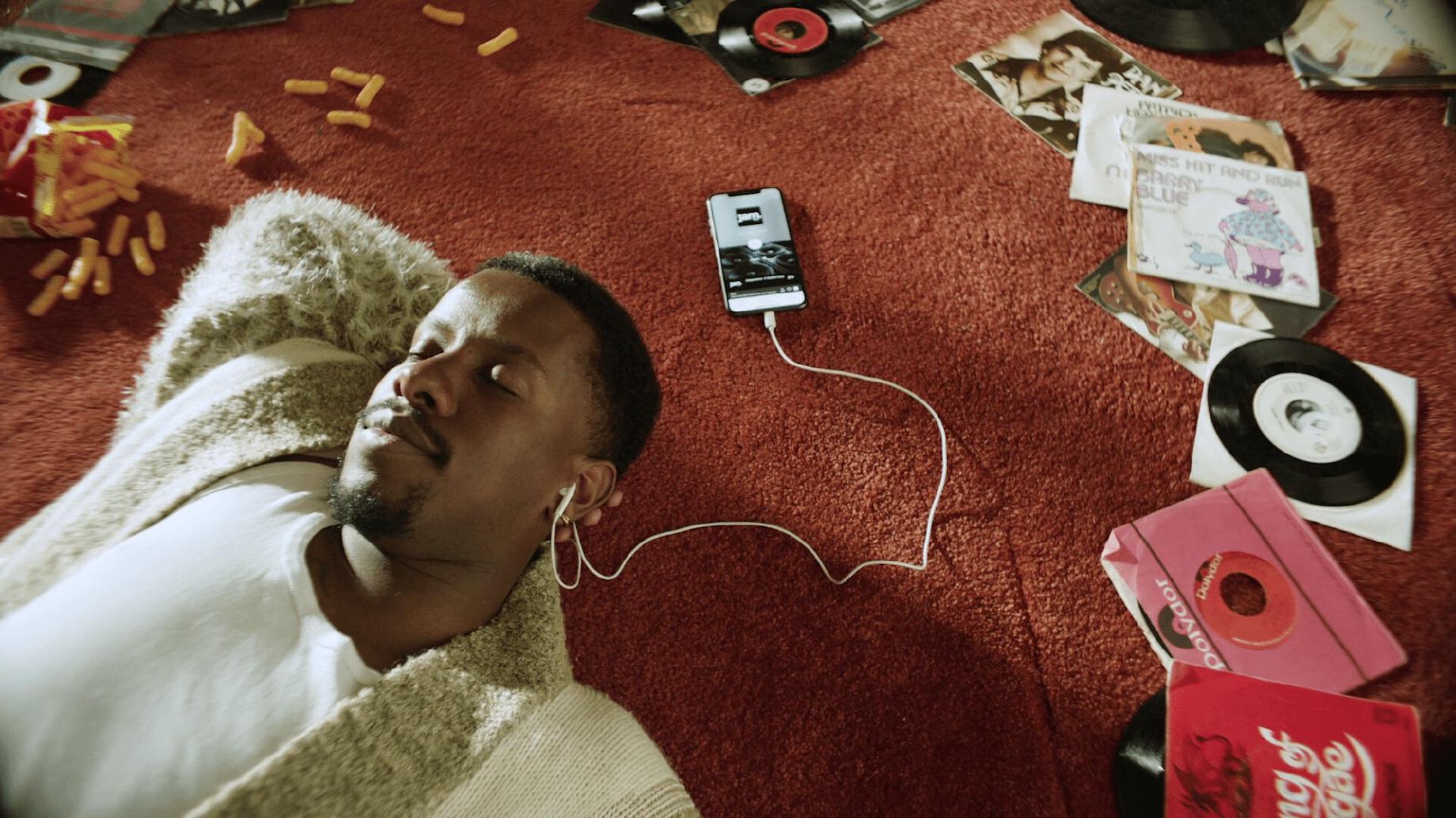 Man laying on a carpet listening to music