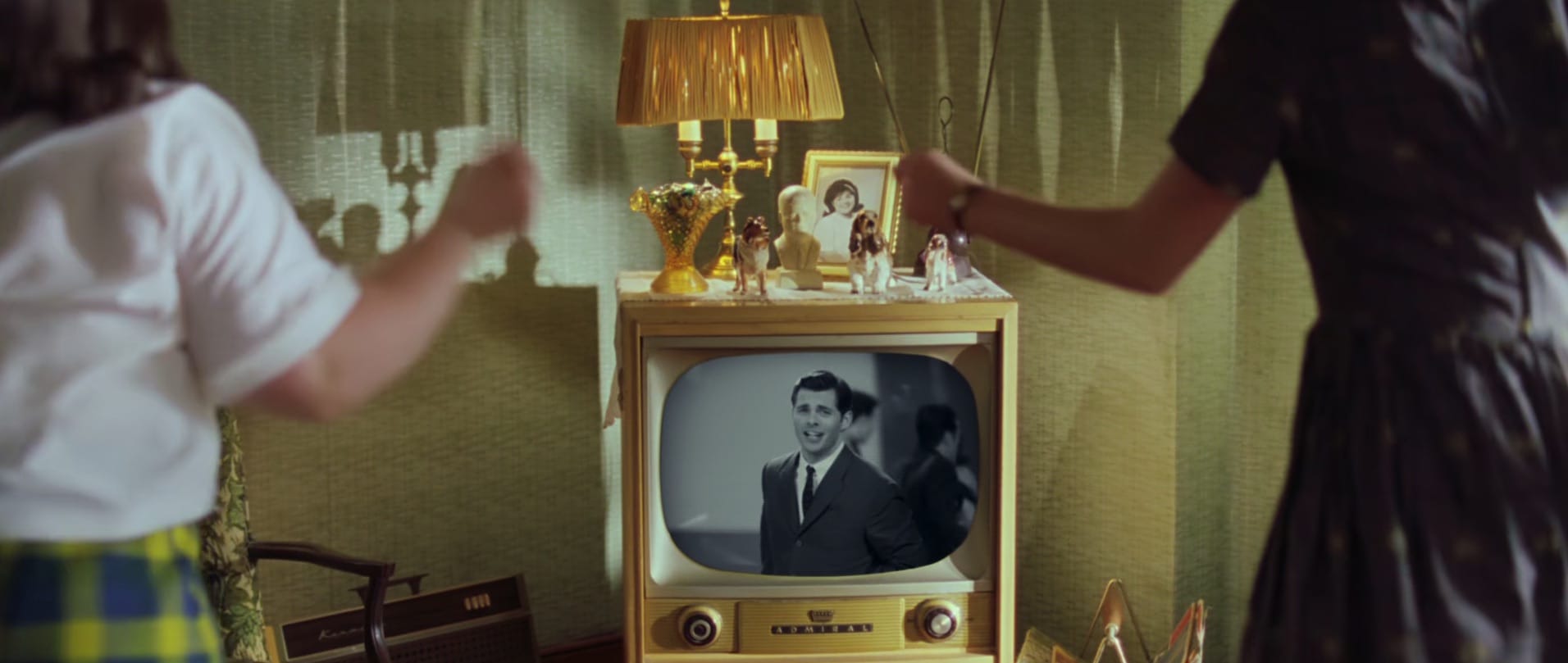 Two women dancing as they watch someone sing on TV