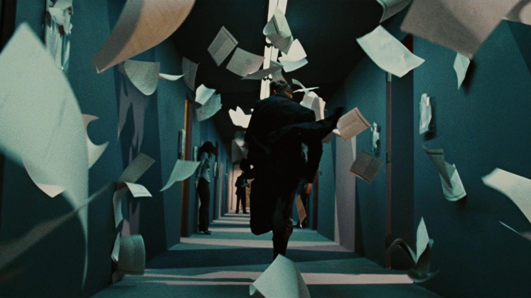 Man running through a corridor of flying paperwork