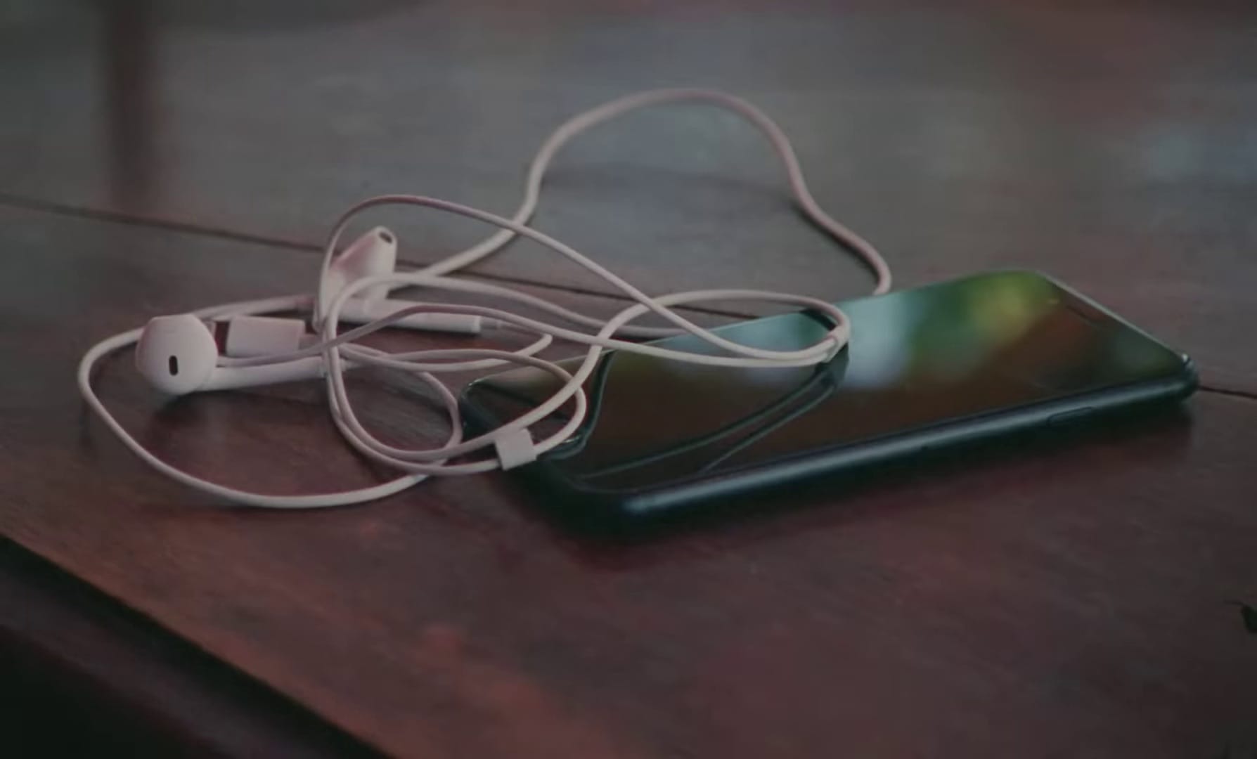 Smartphone on a table with earphones plugged inside