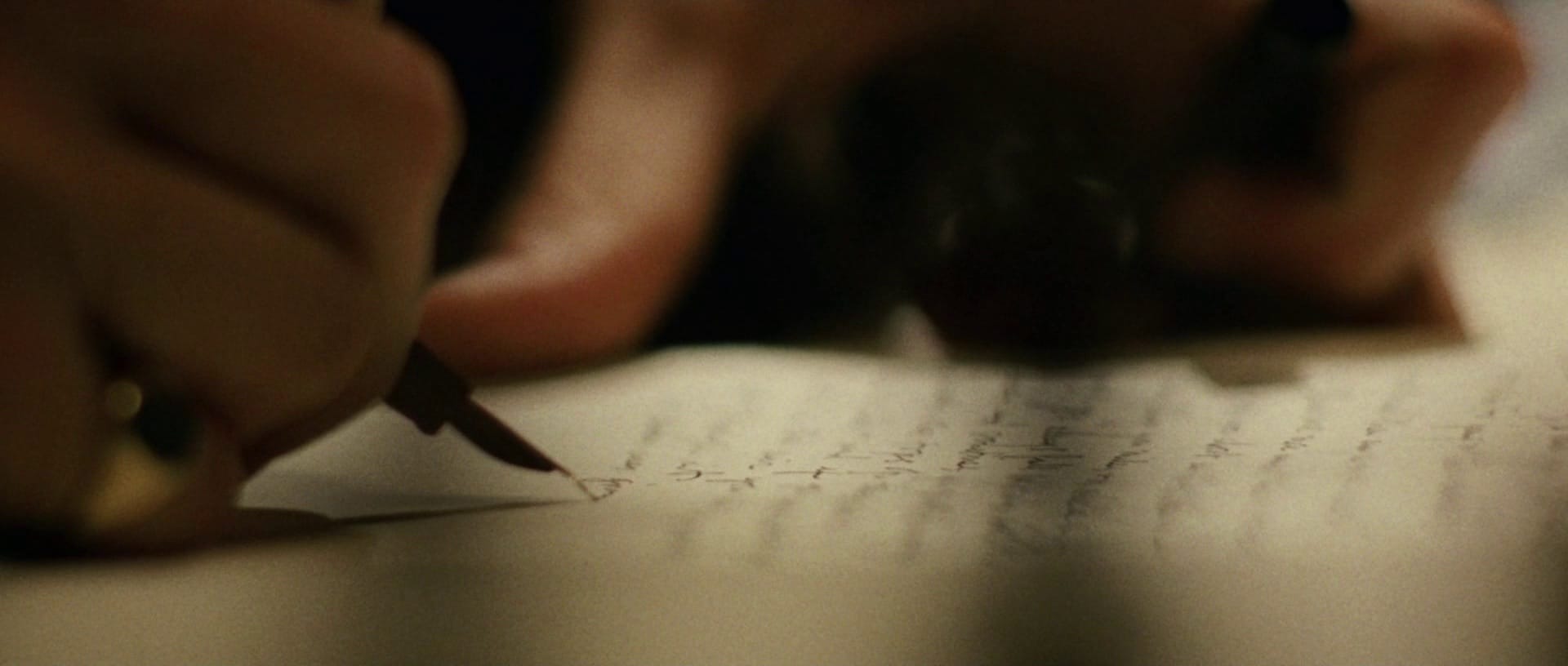 Image of someone signing a document with an ink pen in warm lighting