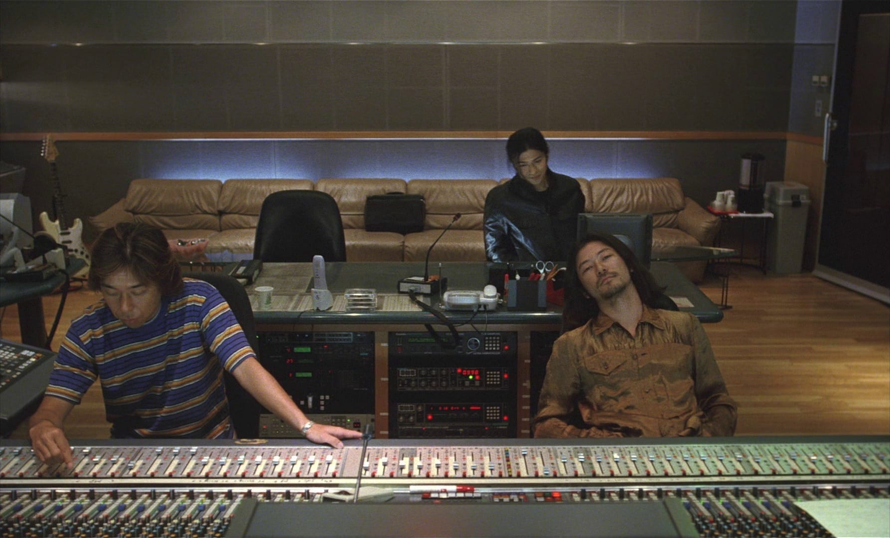 Three men in a music studio behind the console